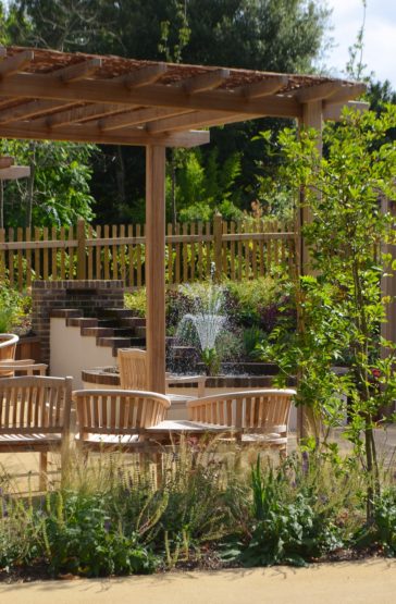 A view through the pergola with the dinning table to the water feature.